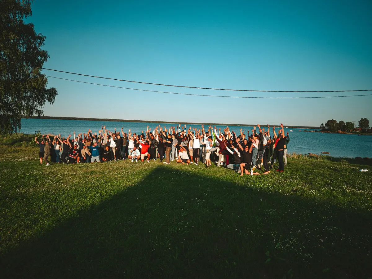 Full team group photo by the lakeside with hands raised