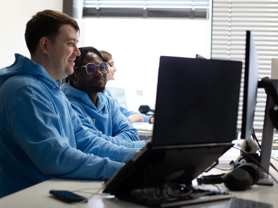 Team members collaborating at workstations in bright office